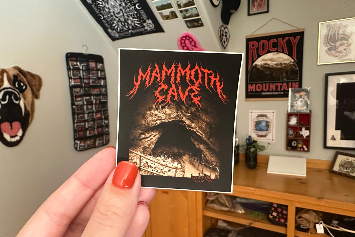 Person holding a 'Mammoth Cave' sticker in a room with various decorations.