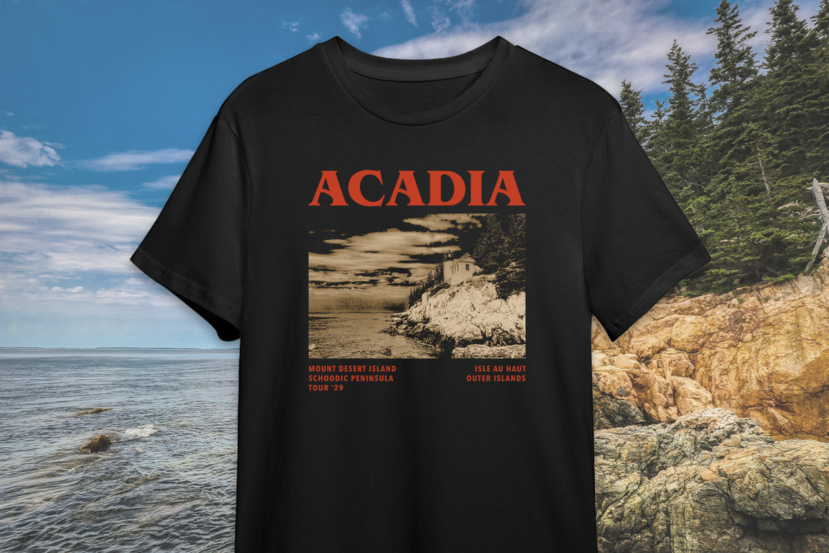 Black t-shirt with 'ACADIA' design featuring a scenic print, displayed on a photo background.