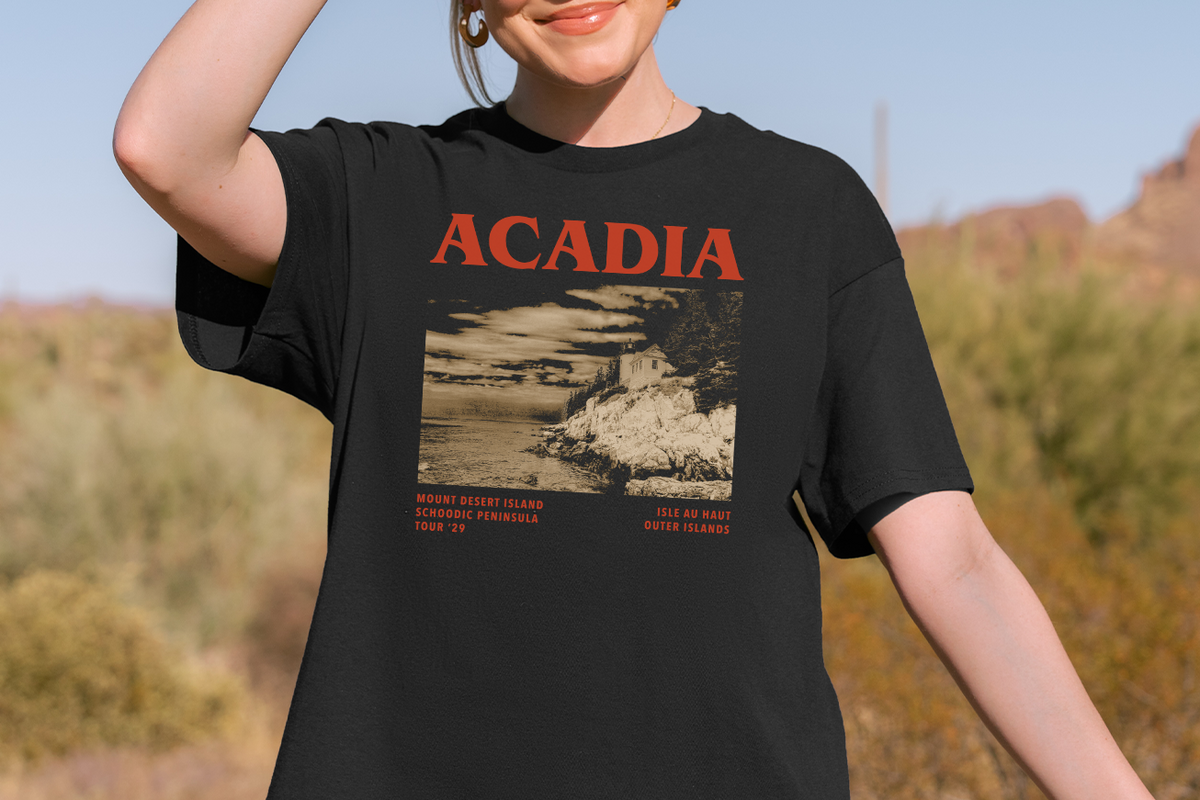 Person wearing a black t-shirt with 'ACADIA' design outdoors