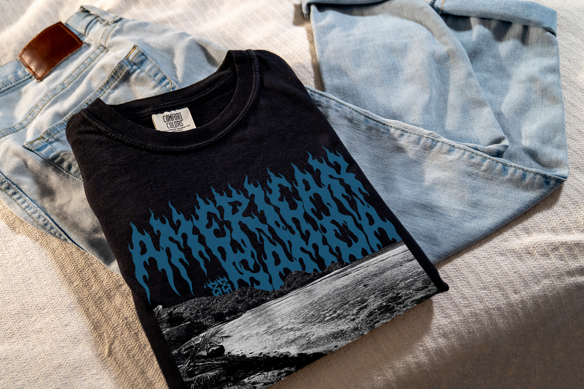 Black t-shirt with blue 'American Samoa' graphic design, folded and placed on light blue jeans.