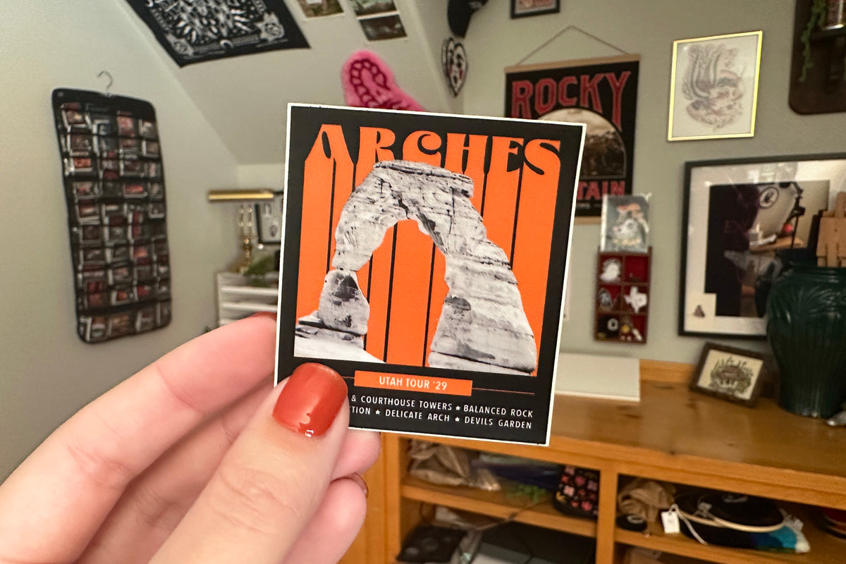 Hand holding an 'Arches' sticker with a room in the background
