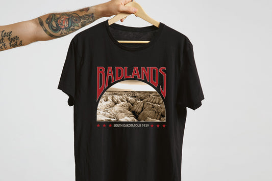 Black t-shirt with 'Badlands' graphic design on a hanger against a white background