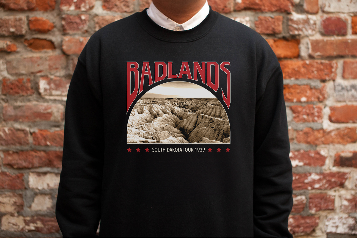 Person wearing a black sweatshirt with 'Badlands' graphic design against a brick wall.