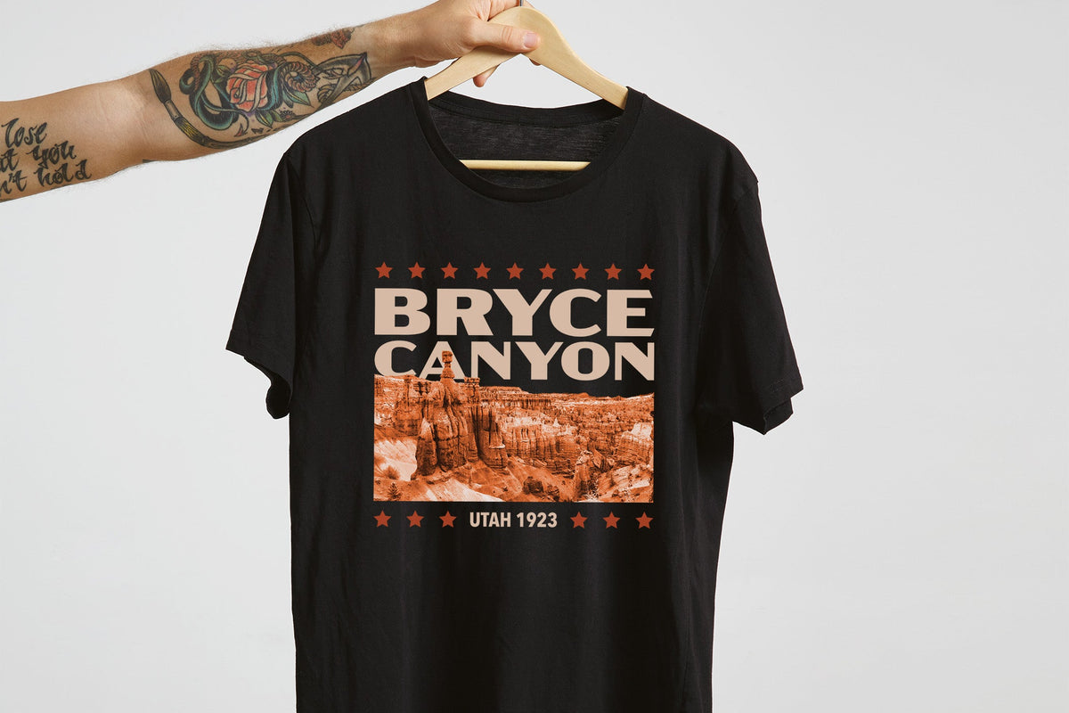 Black t-shirt with 'Bryce Canyon' design on a hanger against a white background