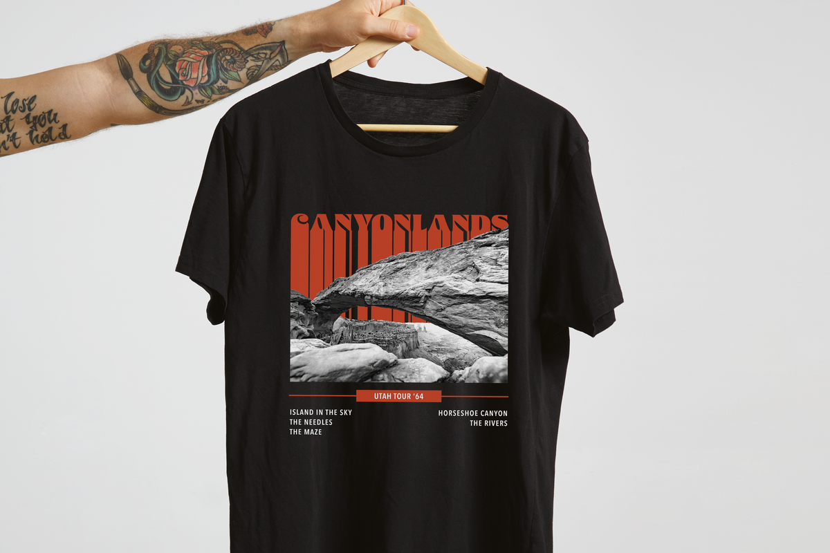 Black t-shirt with Canyonlands national park graphic on a hanger against a light gray background