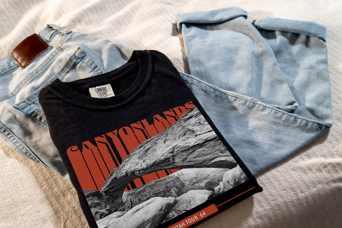 Black t-shirt with a 'Canyonlands' graphic design, laying on jeans