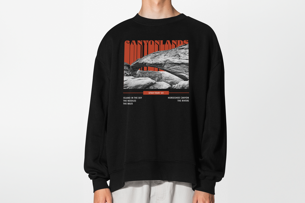 A person wearing a black sweatshirt with a 'Canyonlands' design, standing in front of a white background