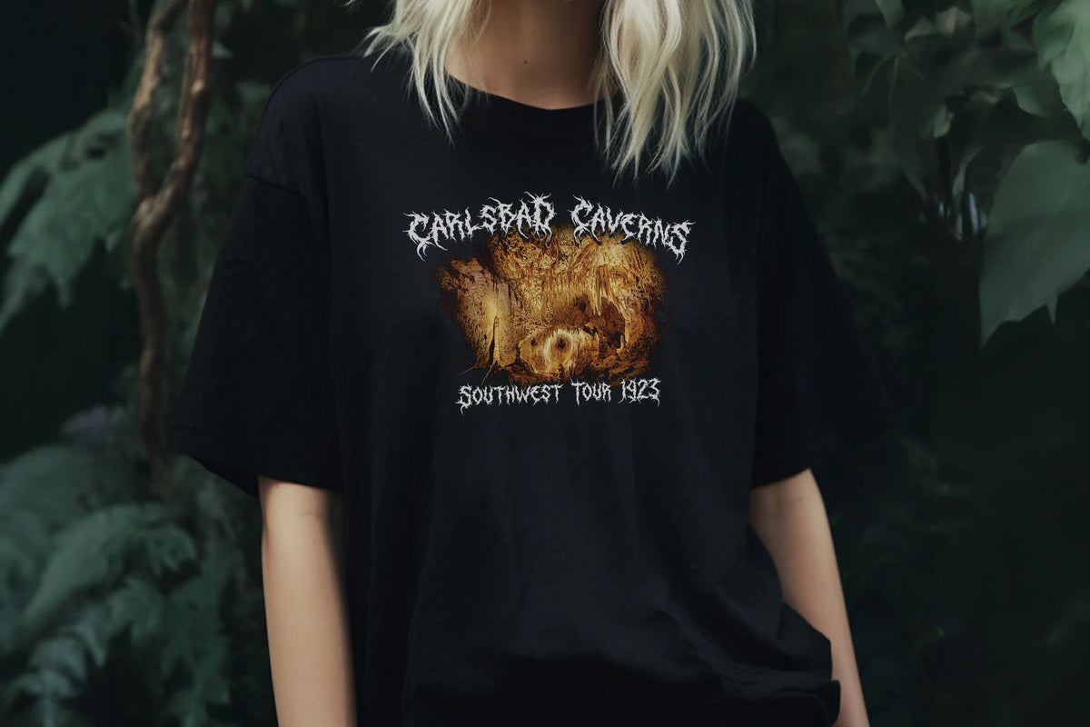 Person wearing a black t-shirt with 'Carlsbad Caverns' design against a dark background