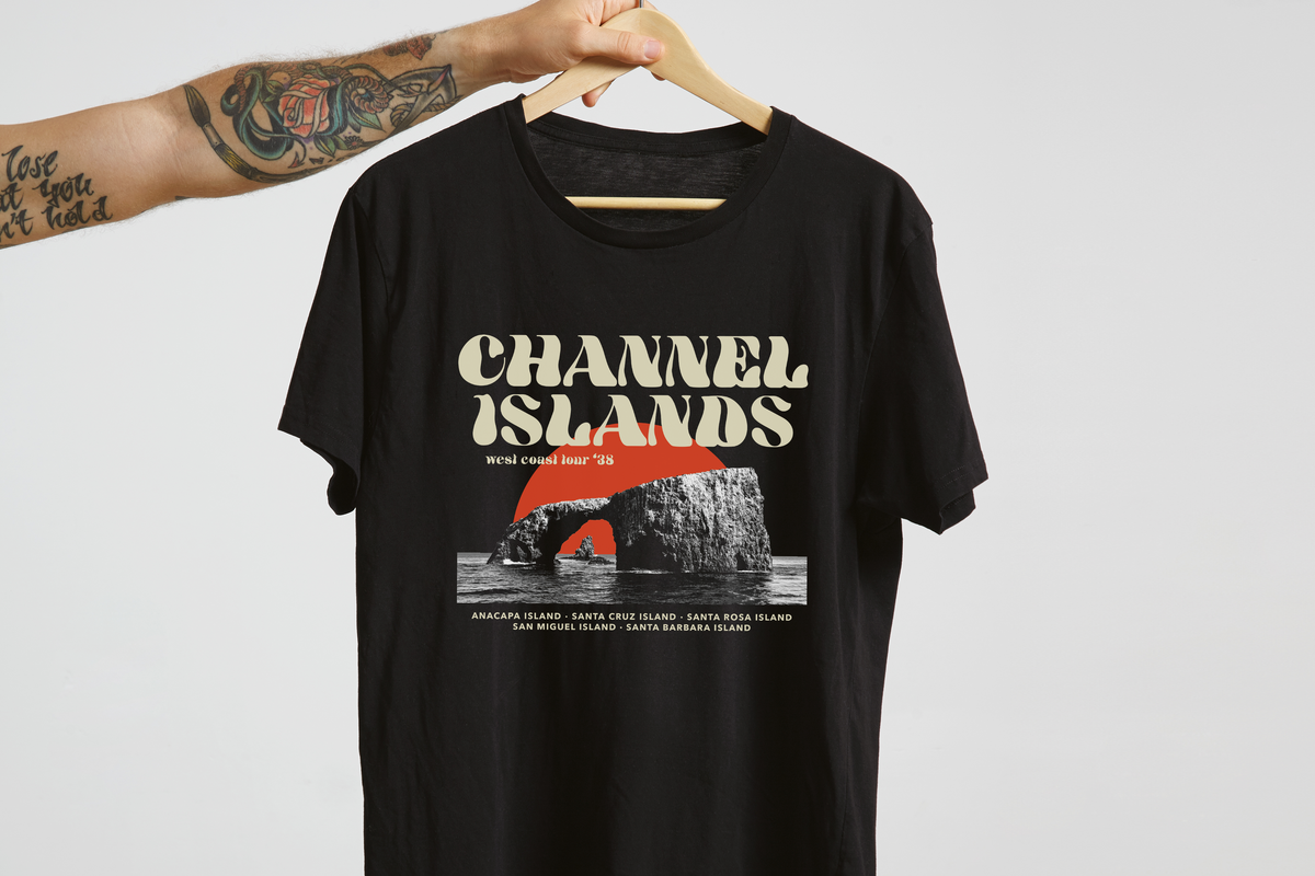 Black t-shirt with 'Channel Islands' graphic design on a hanger against a light gray background