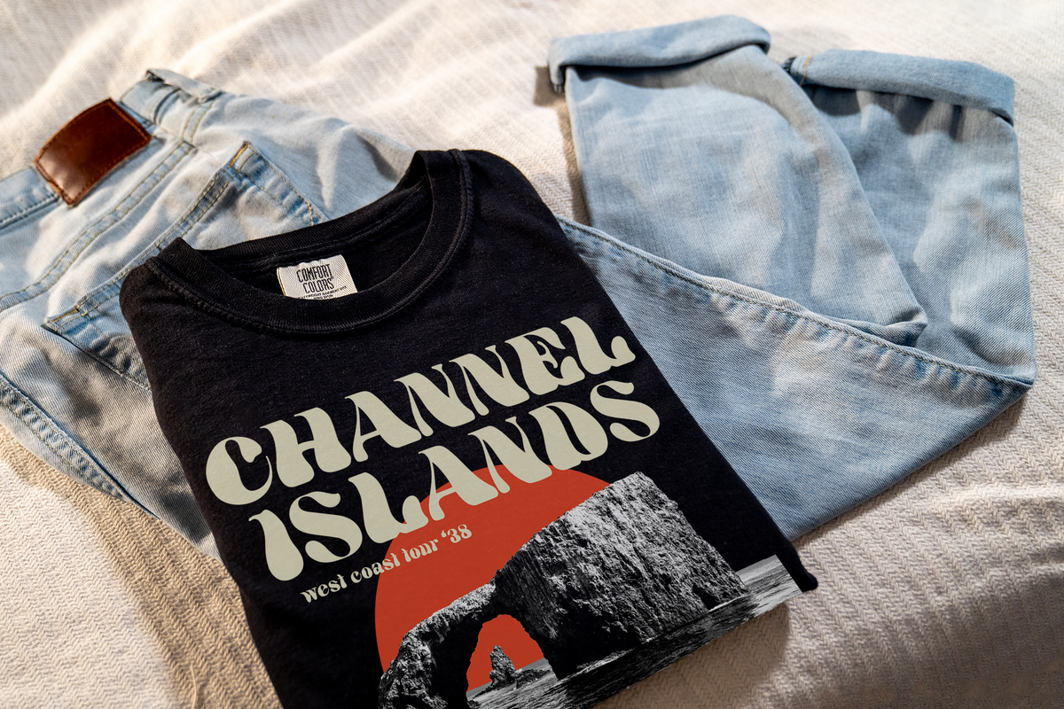Black t-shirt with 'Channel Islands' design, laying on denim jeans