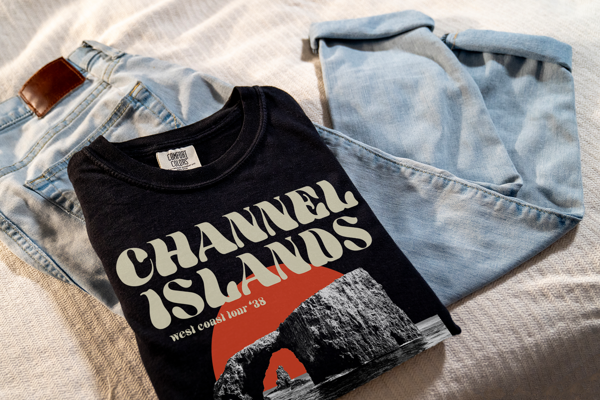 Black t-shirt with 'Channel Islands' design, laying on jeans