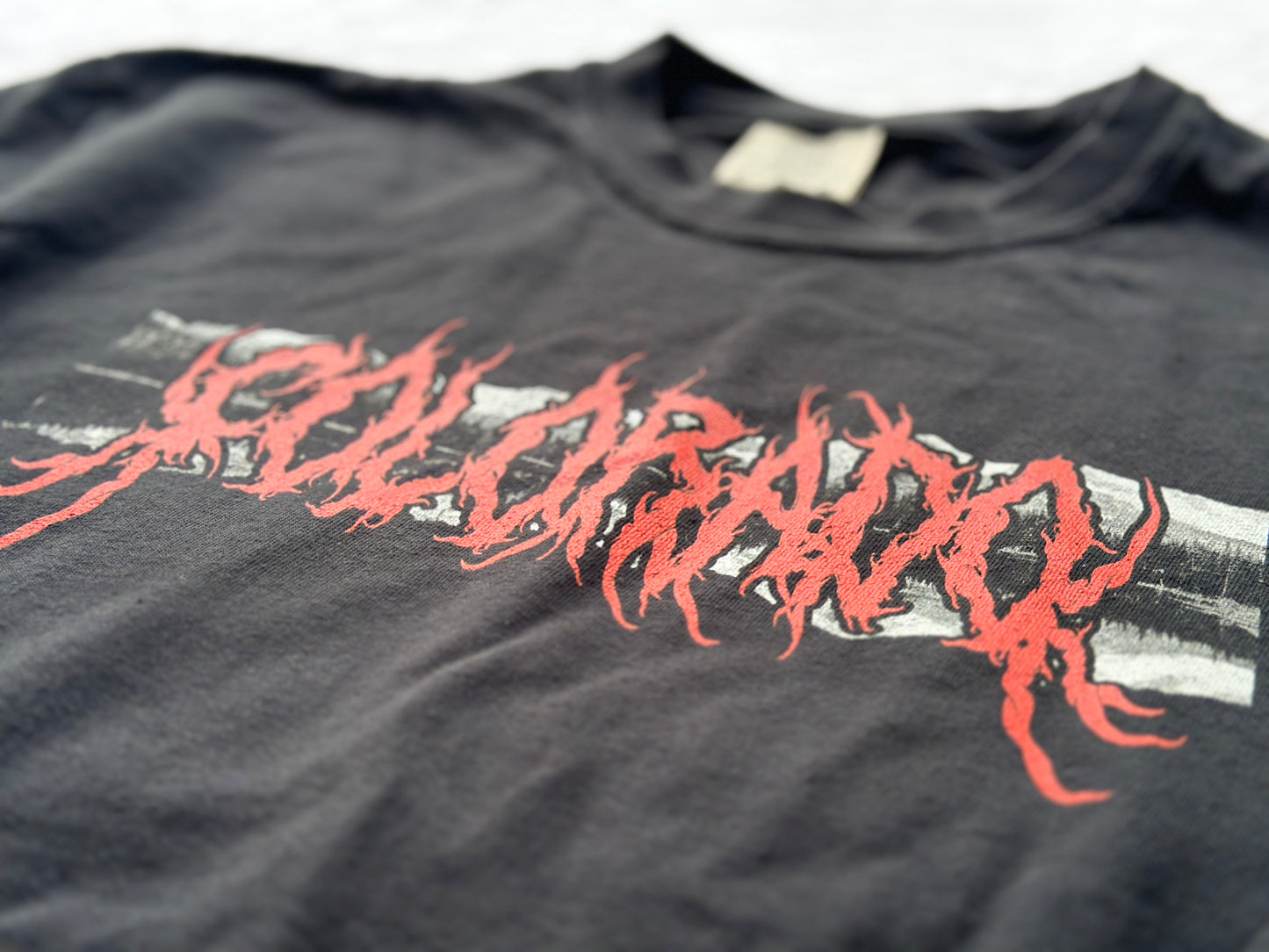 Black shirt with a red and white 'Colorado' graphic, on a white surface