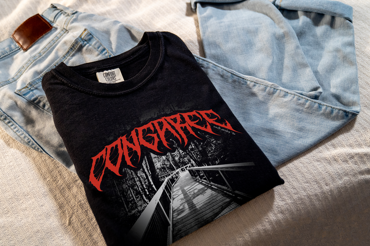 Black t-shirt with 'Congaree' graphic laid on jeans.