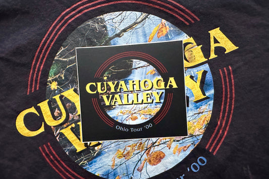 Black sticker with 'Cuyahoga Valley' graphic design featuring a scenic print and text, in front of a dark background