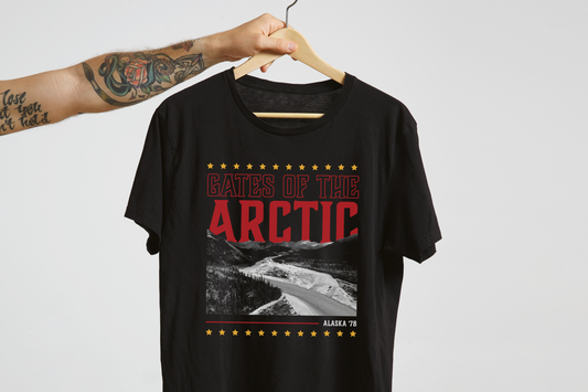 Black t-shirt with 'Gates of the Arctic' graphic design on a hanger against a light gray background.