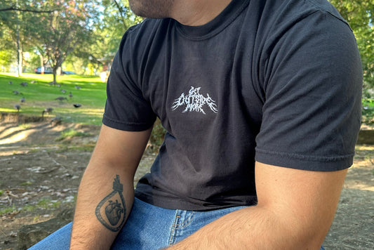 Person wearing a black t-shirt with a white logo in an outdoor setting