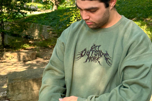 Man wearing a green sweatshirt with a black graphic design outdoors