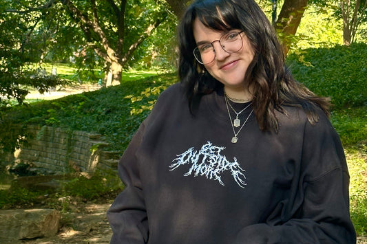 Person wearing a black sweatshirt with white text in an outdoor setting