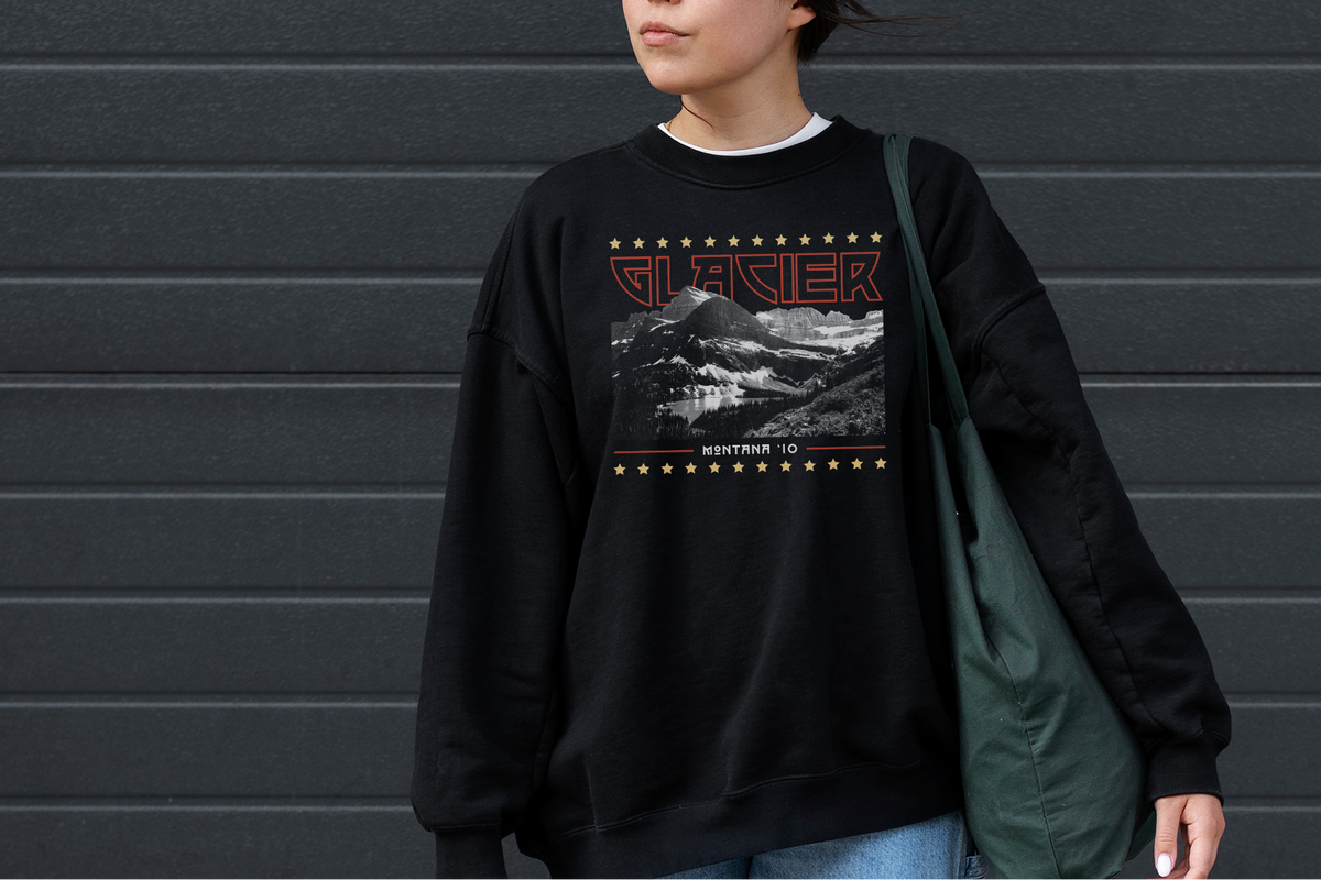 Person wearing a black sweatshirt with a 'Glacier' graphic and text, standing against a gray wall.