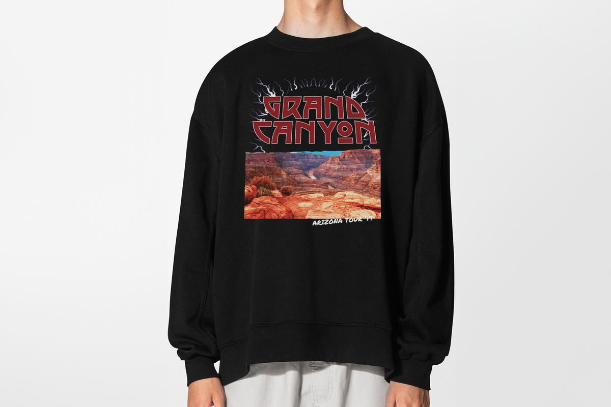 A person wearing a black sweatshirt with 'Grand Canyon' graphic, in front of a white background