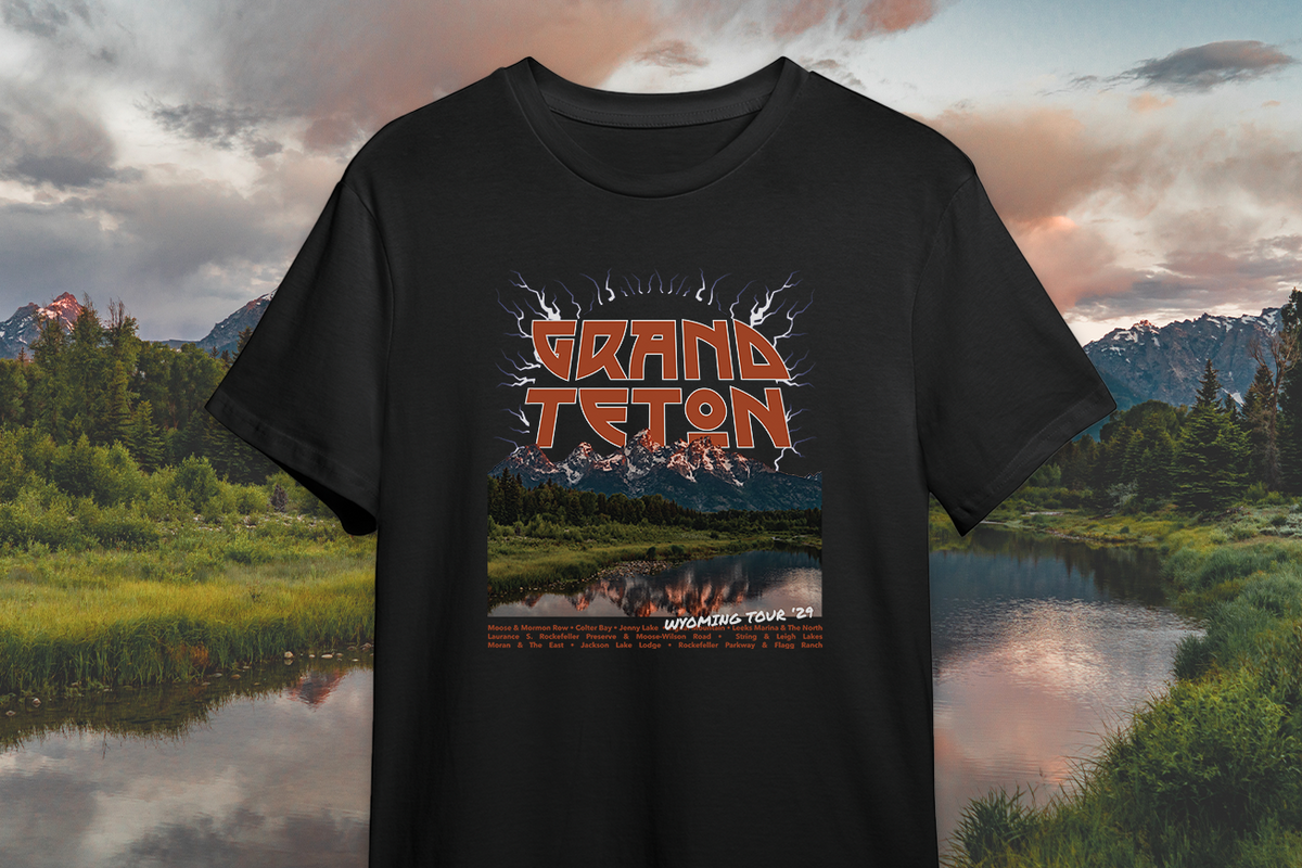 Black t-shirt with Grand Teton design against a scenic background of mountains and lake.