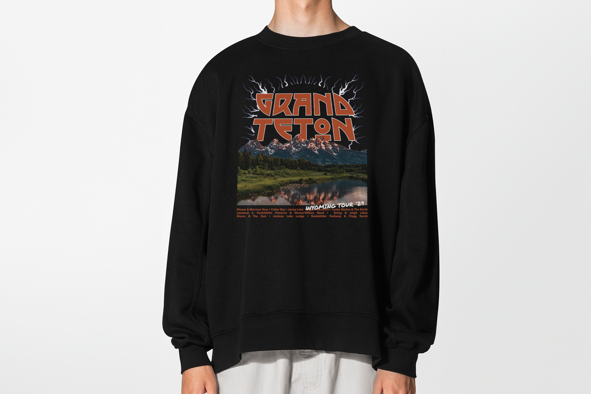 A person wearing a black sweatshirt with 'Grand Teton' graphic design, in front of a white background