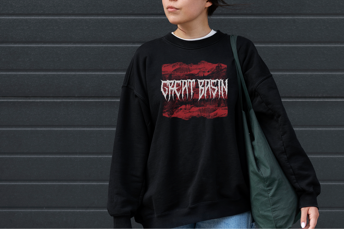 Person wearing a black sweatshirt with 'Great Basin' design against a gray wall