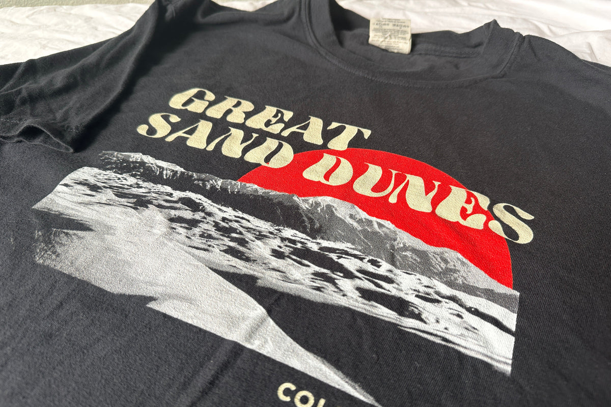 Black t-shirt with 'Great Sand Dunes Colorado' graphic design on a white background