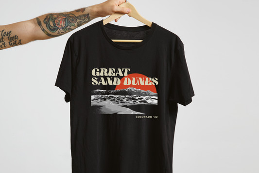 Black t-shirt with 'Great Sand Dunes' design on a hanger against a white background