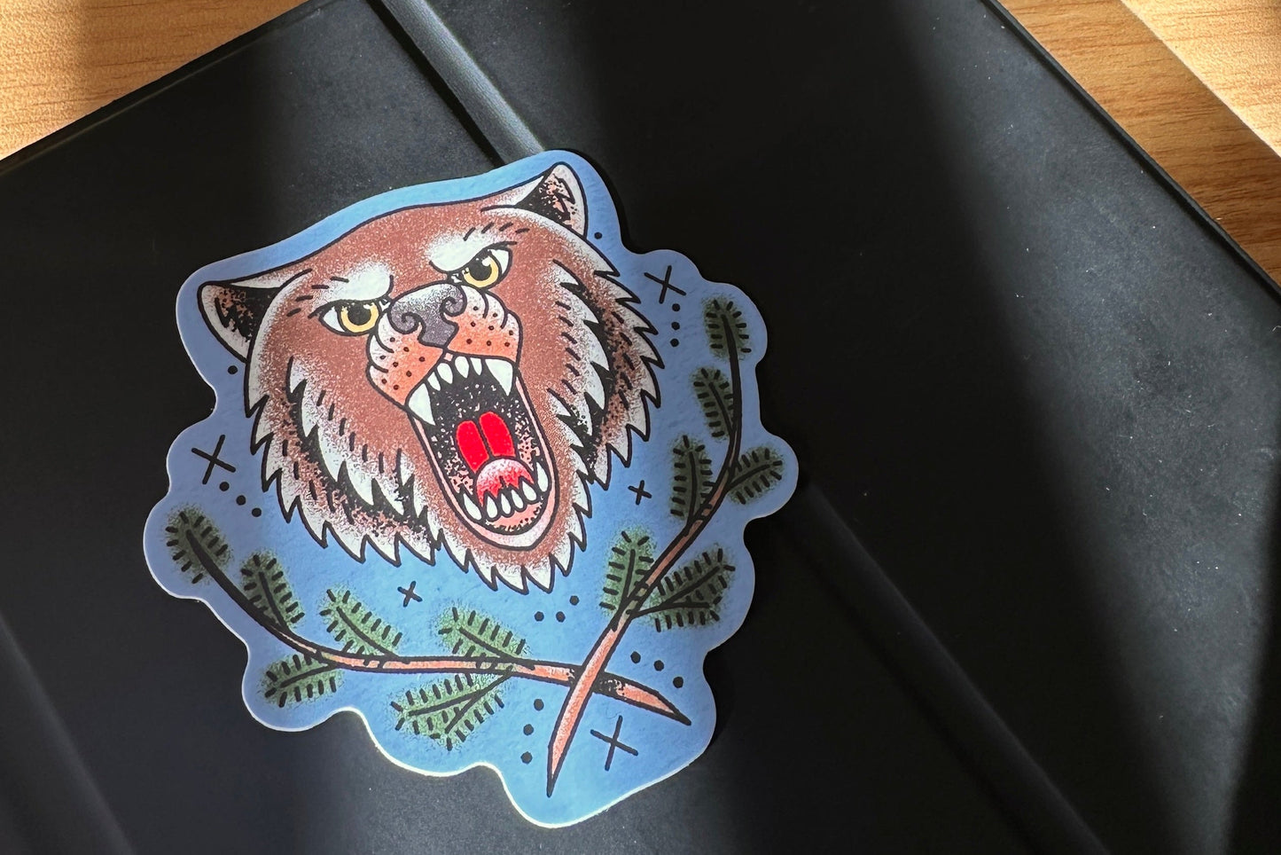 Sticker of a bear with green leaves on a black surface