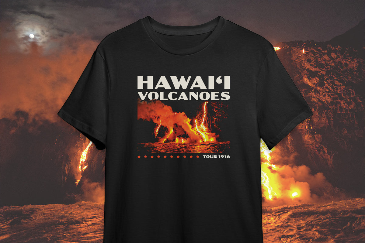 A black t-shirt with a 'Hawai'i Volcanoes' graphic design, in front of a volcano background