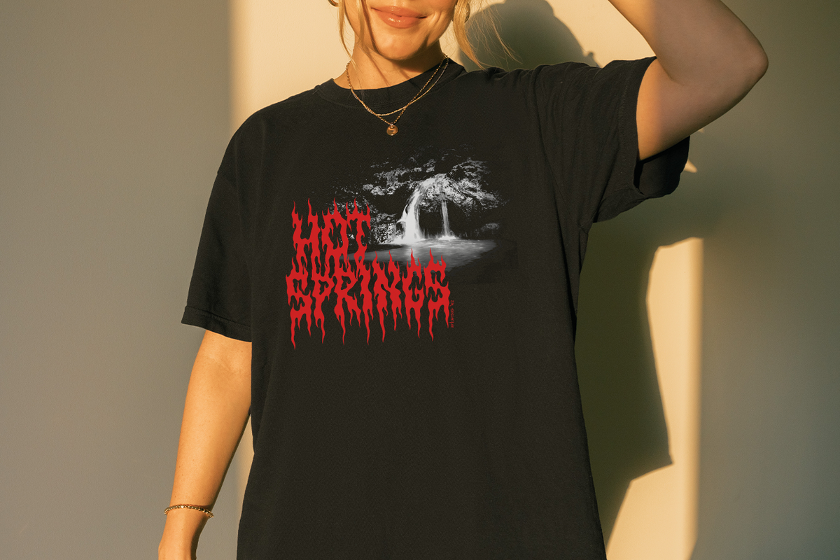 Person wearing a black t-shirt with 'Hot Springs' design and red text against a neutral background