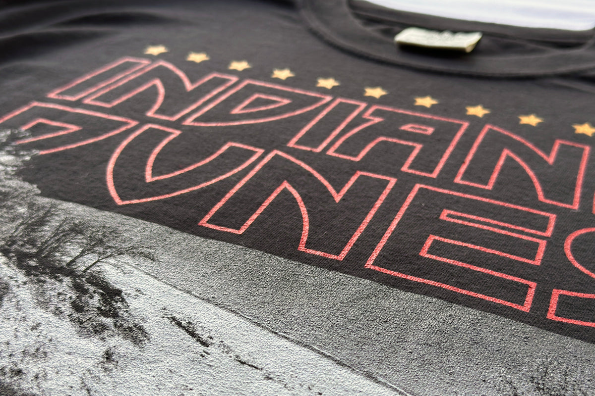 Black t-shirt with red text 'INDIANA DUNES' on a textured surface