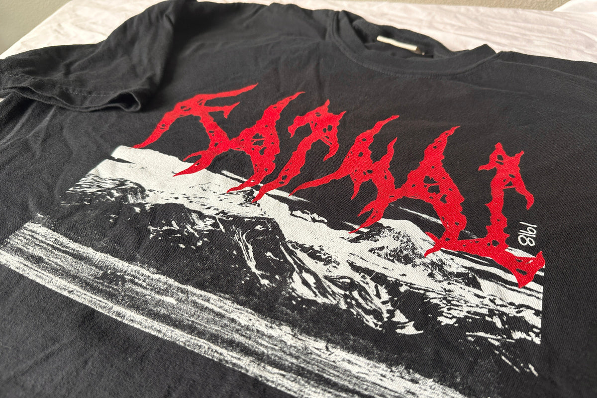 Black t-shirt with red and white 'Katmai' graphic design on a bed