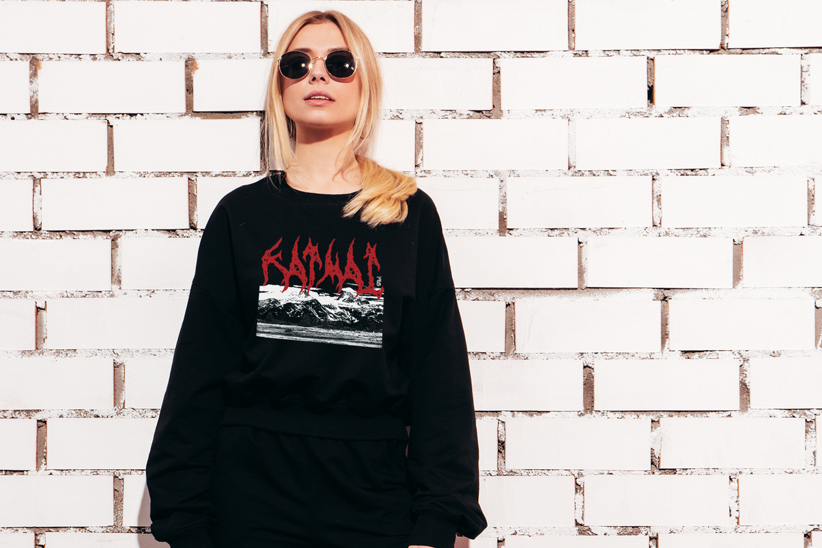 Person wearing a black sweatshirt with a 'Katmai' graphic design against a white brick wall