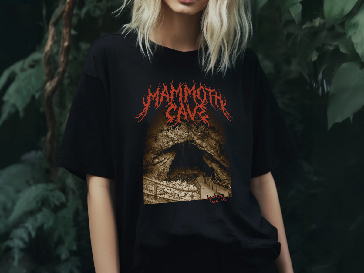 A person wearing a black t-shirt with a 'Mammoth Cave' graphic design, standing in front of a plant background