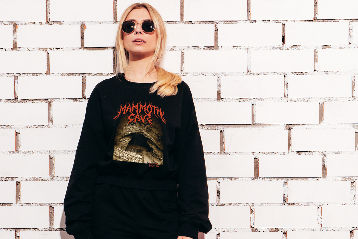 Person wearing a black sweatshirt with 'Mammoth Cave' design against a brick wall.