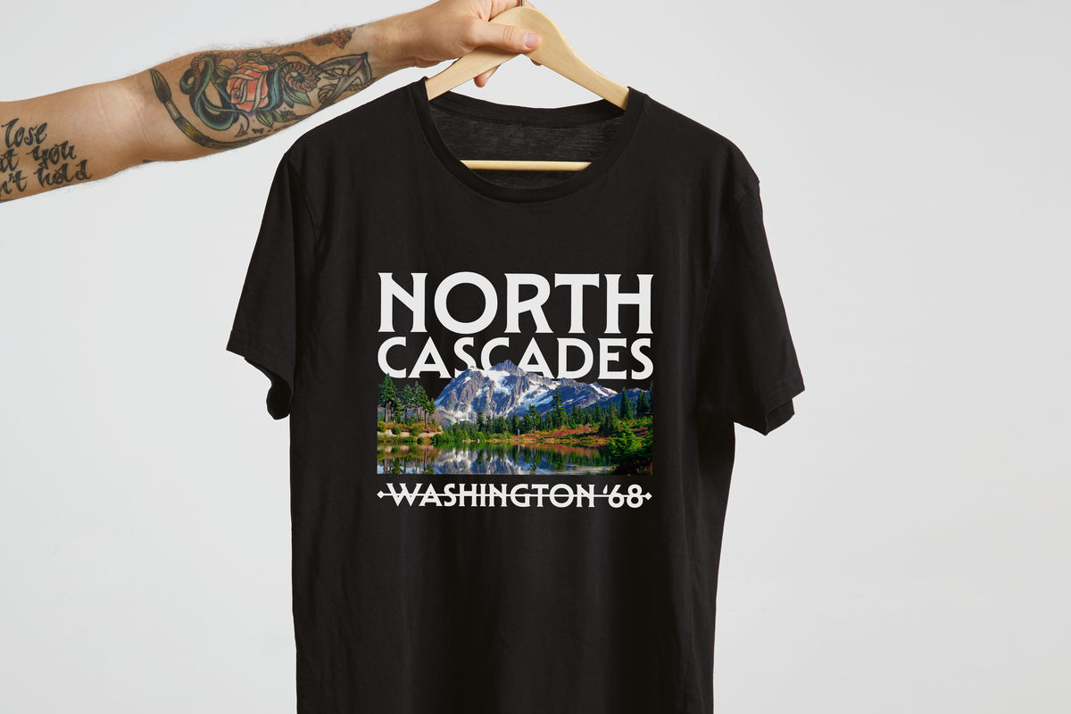 Black t-shirt with 'North Cascades Washington '68' design on a hanger against a light gray background