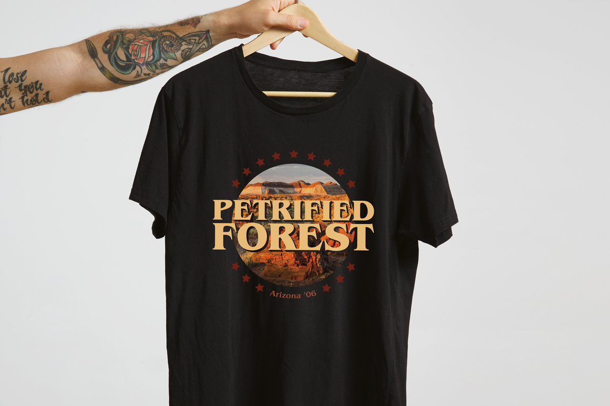 Black t-shirt with 'Petrified Forest' design on a hanger against a white background