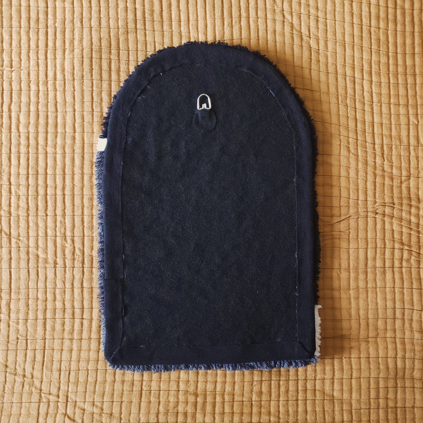 The back of a tufted wall hanging, against a yellow background