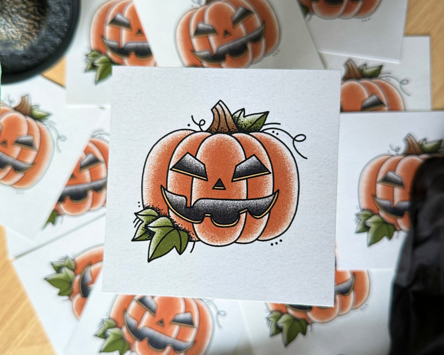 An illustration of a jack-o-lantern, with more art prints in the background