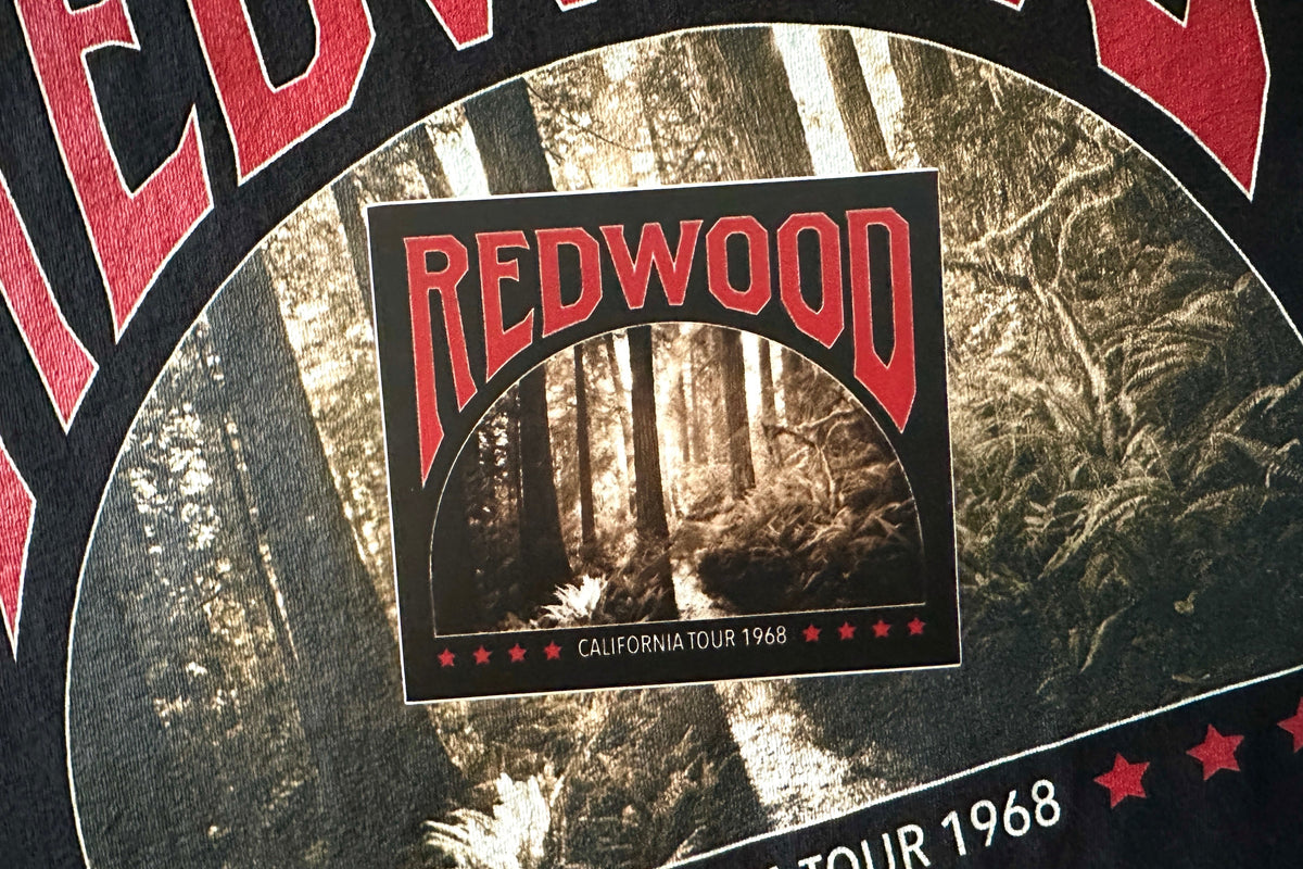 A black sticker with a 'Redwood' graphic design, on a textured background