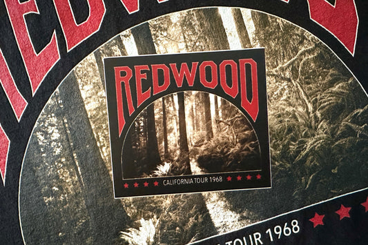 A black sticker with a 'Redwood' graphic design, on a textured background