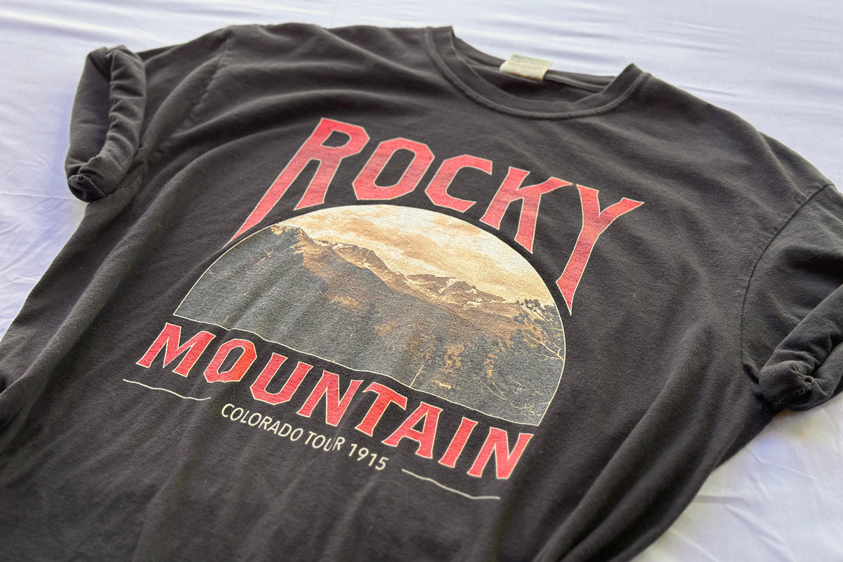 Black t-shirt with 'Rocky Mountain Colorado Tour 1915' graphic on a white surface