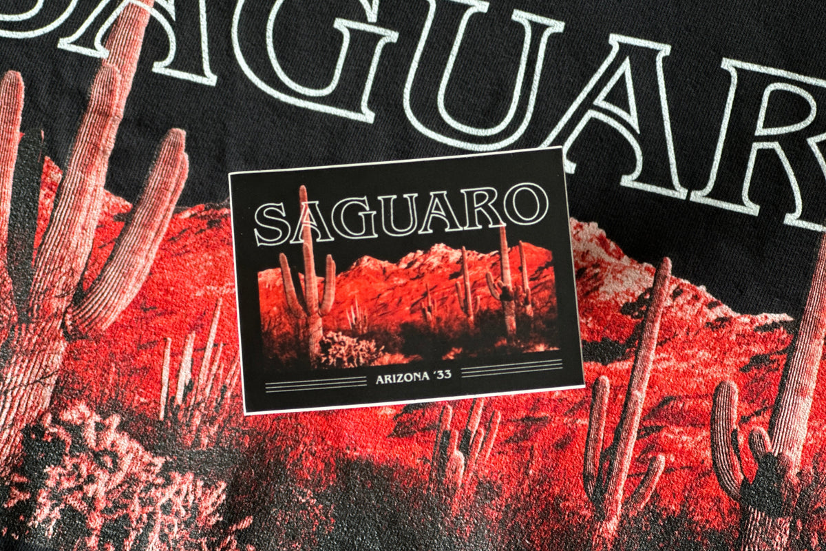 A sticker with 'Saguaro' text and desert landscape illustration on a black background.