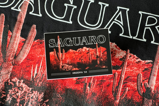 A sticker with 'Saguaro' text and desert landscape illustration on a black background.