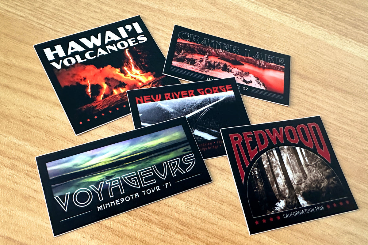 Five stickers featuring different national parks and text on a wooden surface