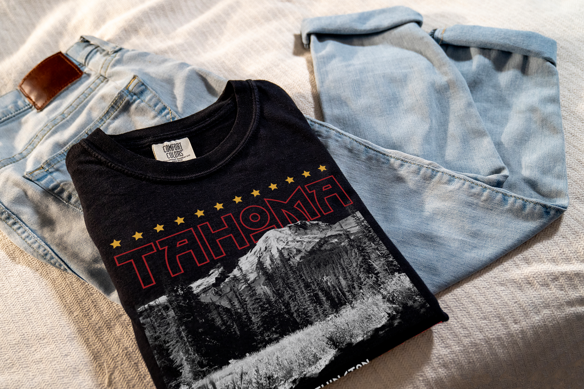 Black t-shirt with 'Tahoma' design, laying on jeans