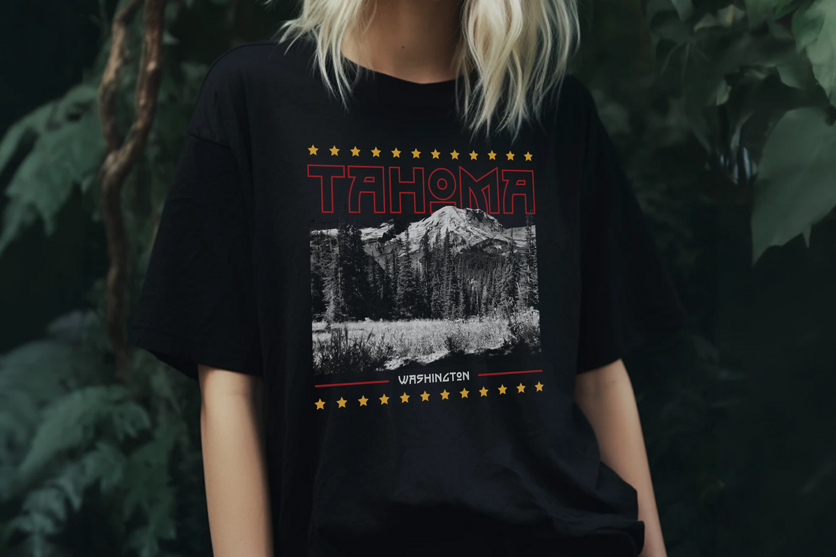 Person wearing a black t-shirt with 'Tahoma, Washington' graphic design, in front of plants