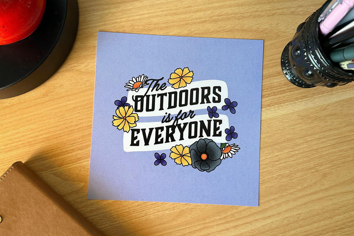 Art print with 'The Outdoors is for Everyone' text on a wooden surface